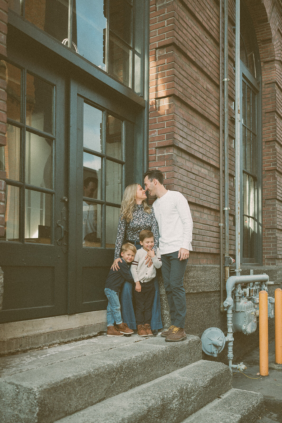 Family standing outside a brick building during a downtown Orange County photo session — natural, documentary-style portraits by family photographer Maria Alcantara.