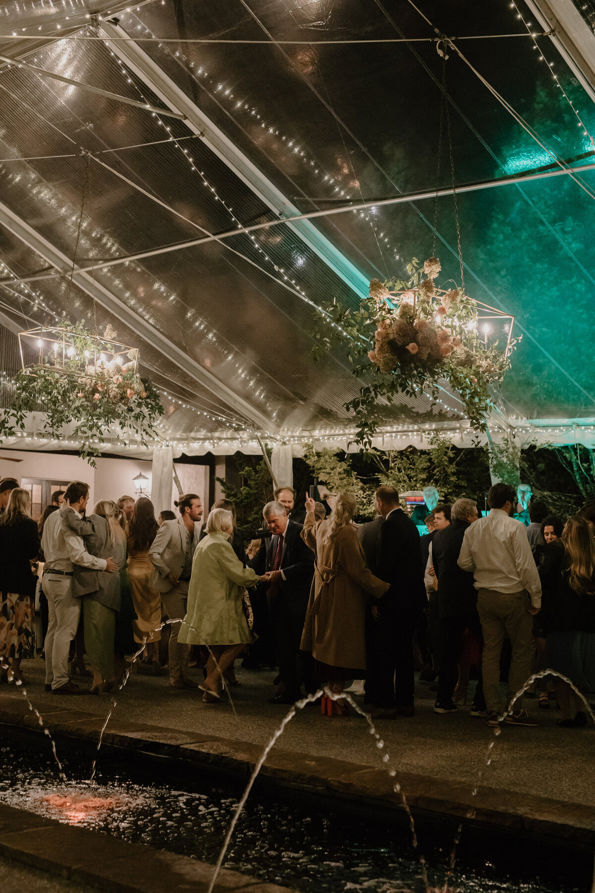 Friends and family dancing with hands in the air, celebrating with the couple.