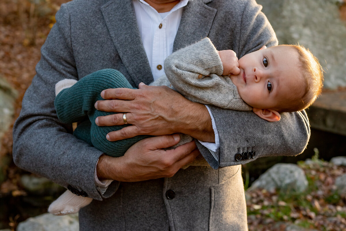 Little boy is being cradled in his grandfather's arms while their family photography session is taking place