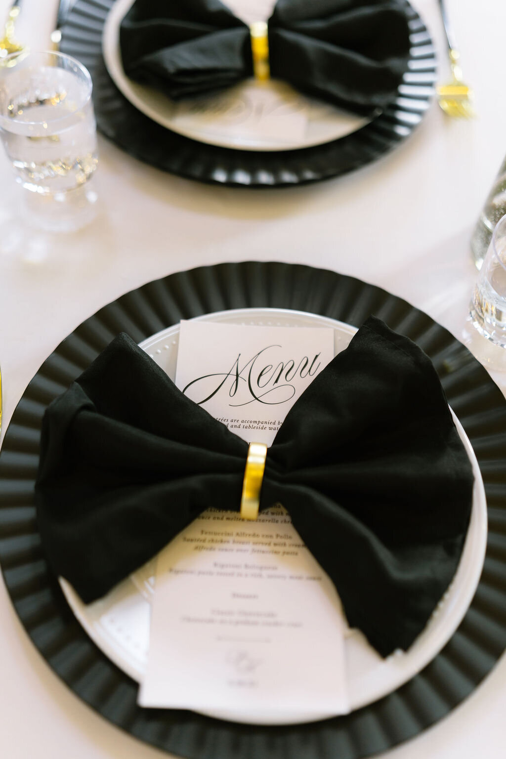 Place setting with a black napkin bow and a menu card