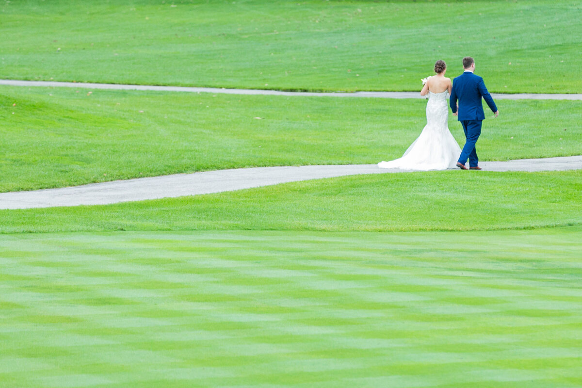 njeri-bishota-lauren-ashley-bride-groom-golf-course-stroll-holding-hands