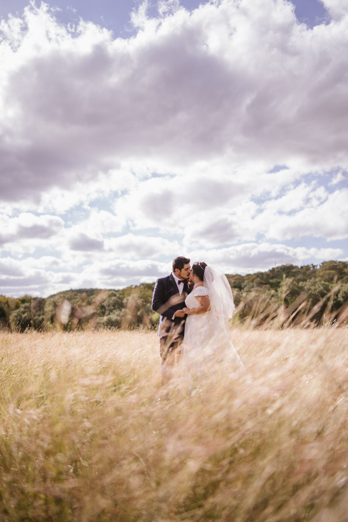 groom and bride kissing in a field and posing for San Antonio Wedding photographer Expose The Heart