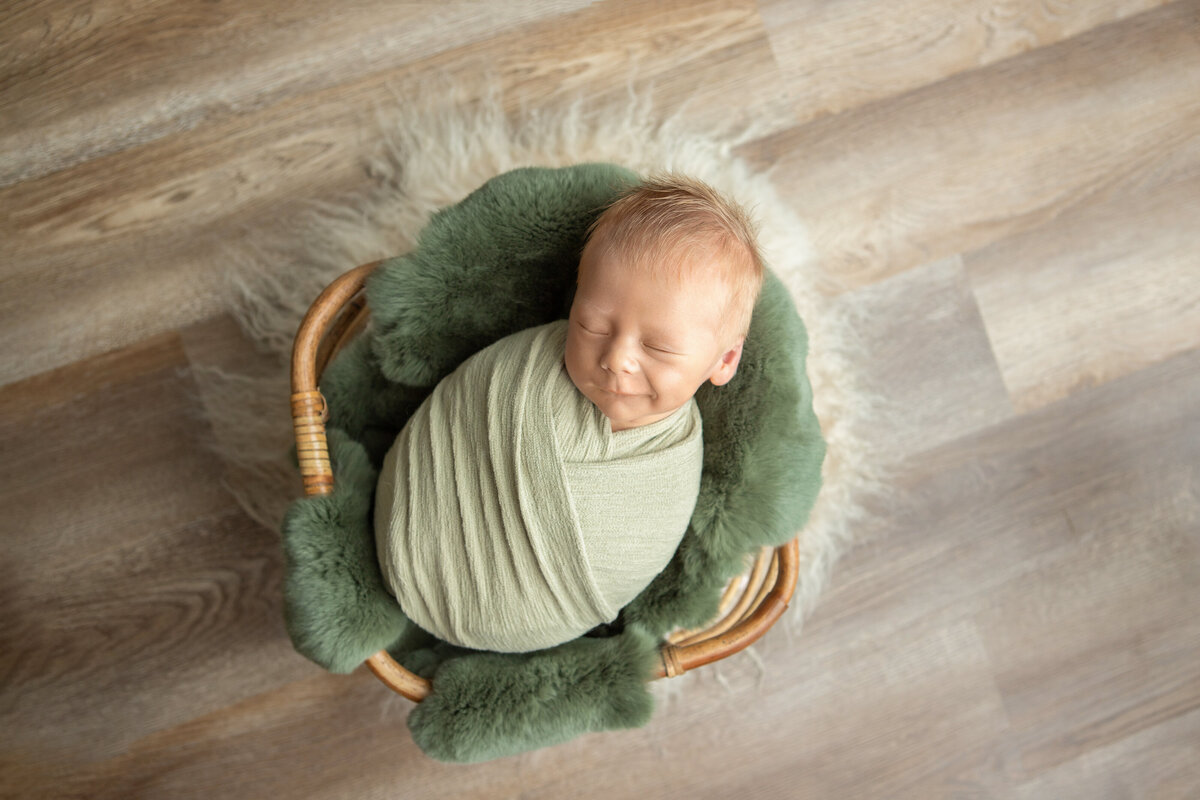 Wrapped newborn olive green layers in the ezra bamboo basket