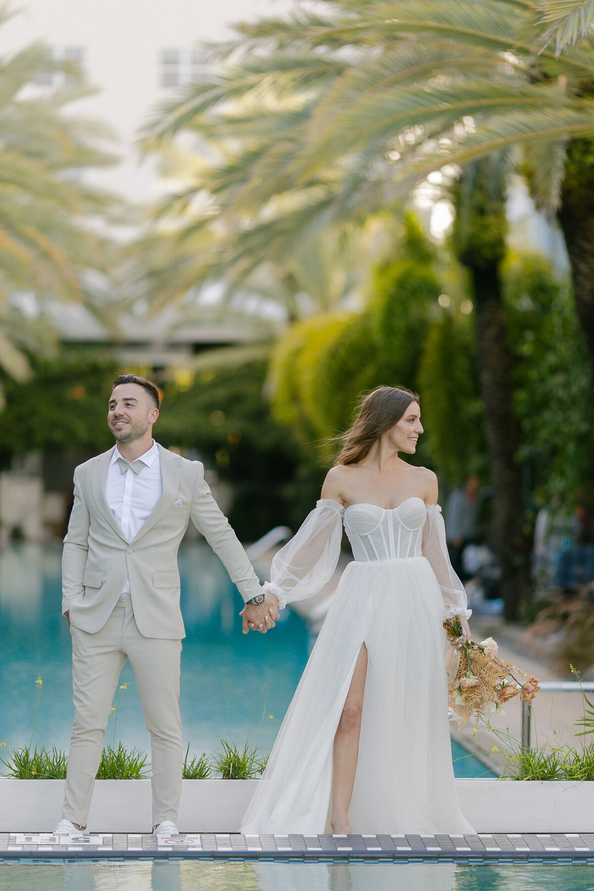 Bride and groom holding hands by the pool, taken by Claudia Amalia, Miami and Florida Keys wedding photographer.