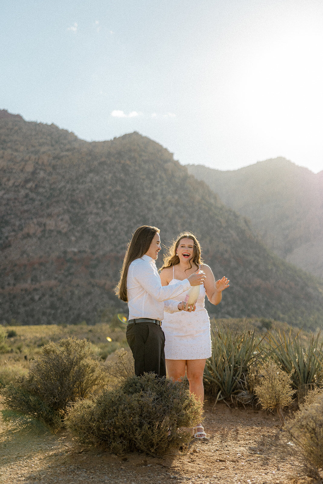 Engaged couple laughing with Nevada mountains in back