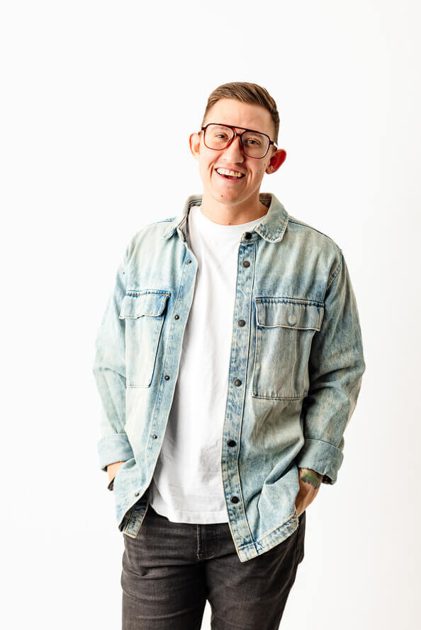 Man in jean shirt puts hands in pockets for his branding photo.