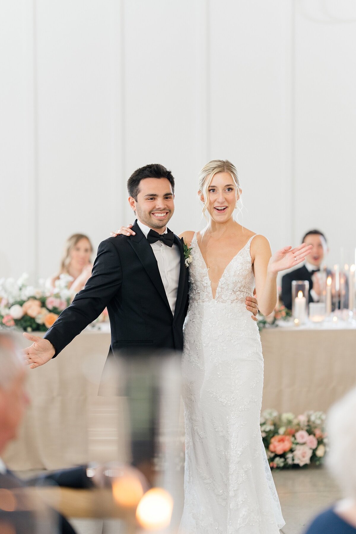 wedding reception with bride and groom wrapping one arm around each other with their other arms out stretched captured by Columbus wedding  photographer