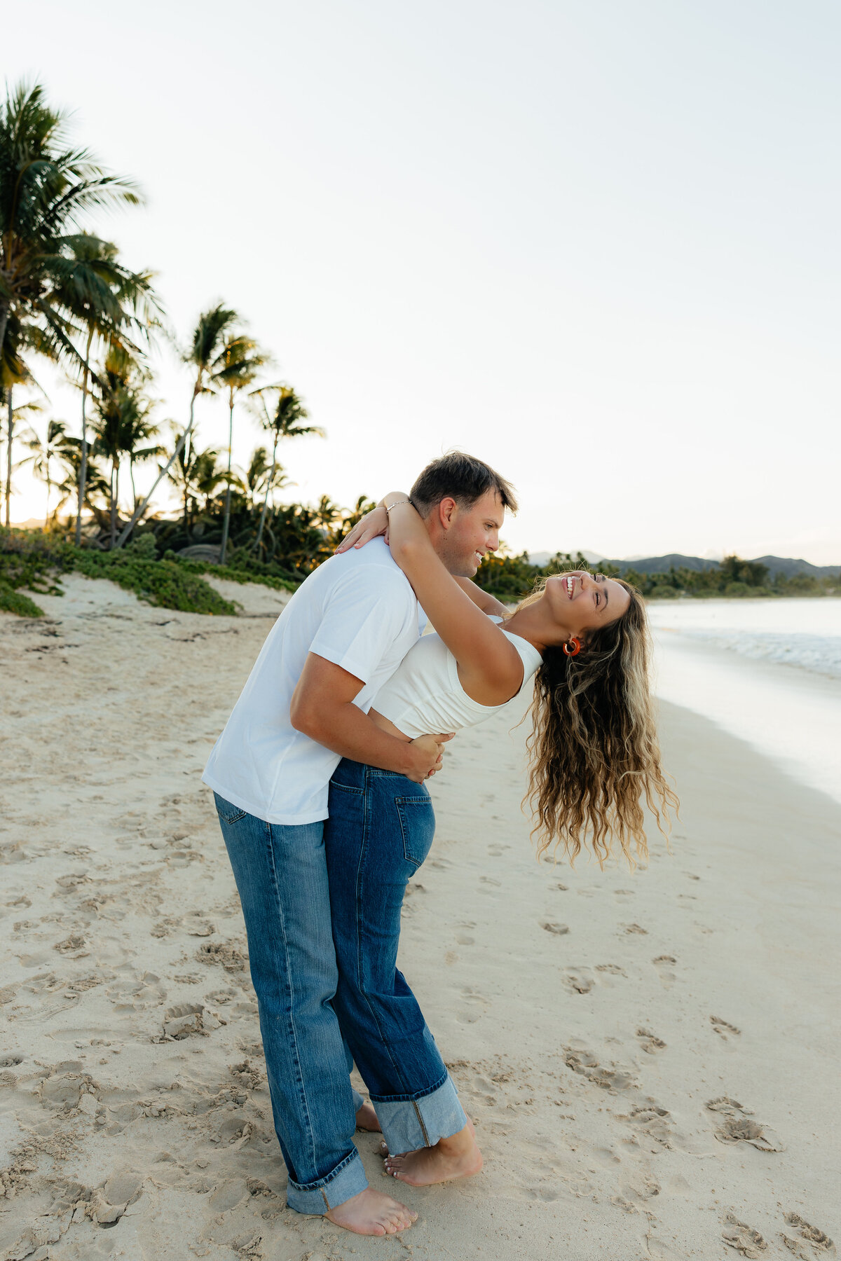 Couple laughing together during golden hour on Kailua beach in Oahu, captured by Lexi Rae Photo.