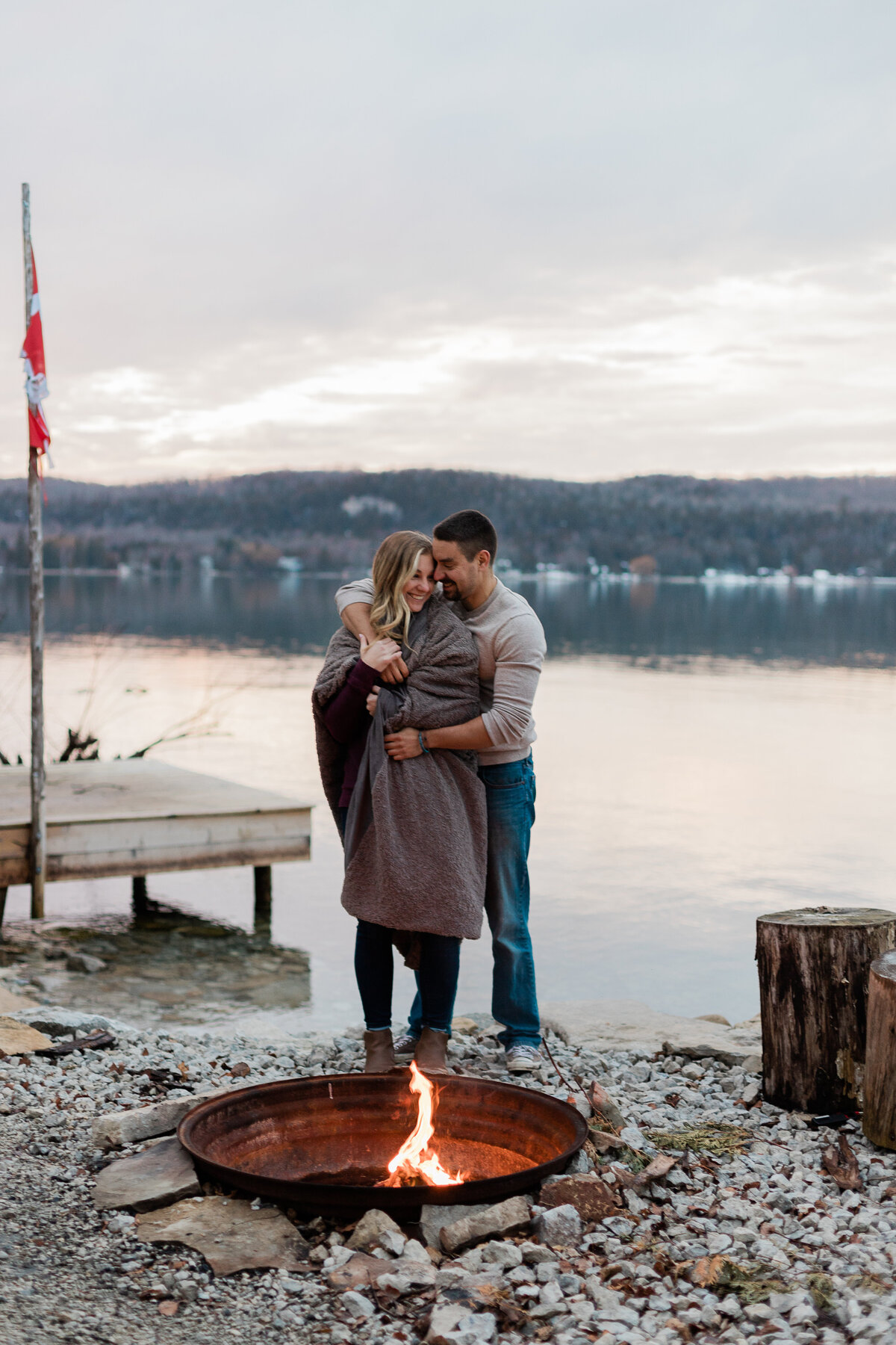 engagement photo by a lake with a fire