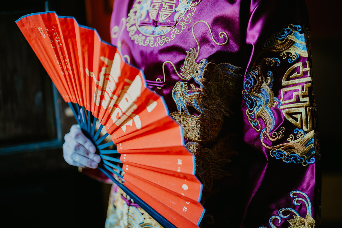 Detail of Chinese traditional outfit with red fan, wedding photographer Tuscany Villa Pitiana.