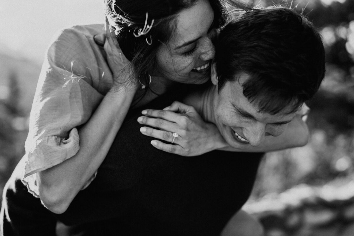 Playful piggyback ride with bride-to-be showing off engagement ring in Breckenridge.