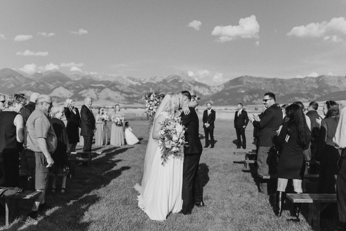 Bride and groom kiss at mountain wedding ceremony