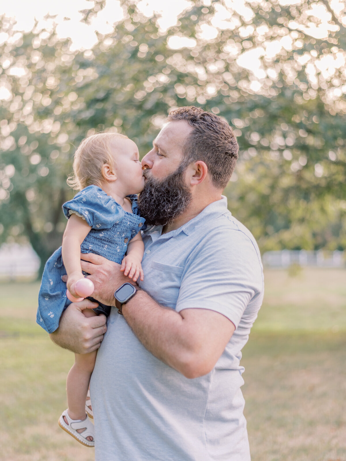 Young girl giving her daddy kisses.