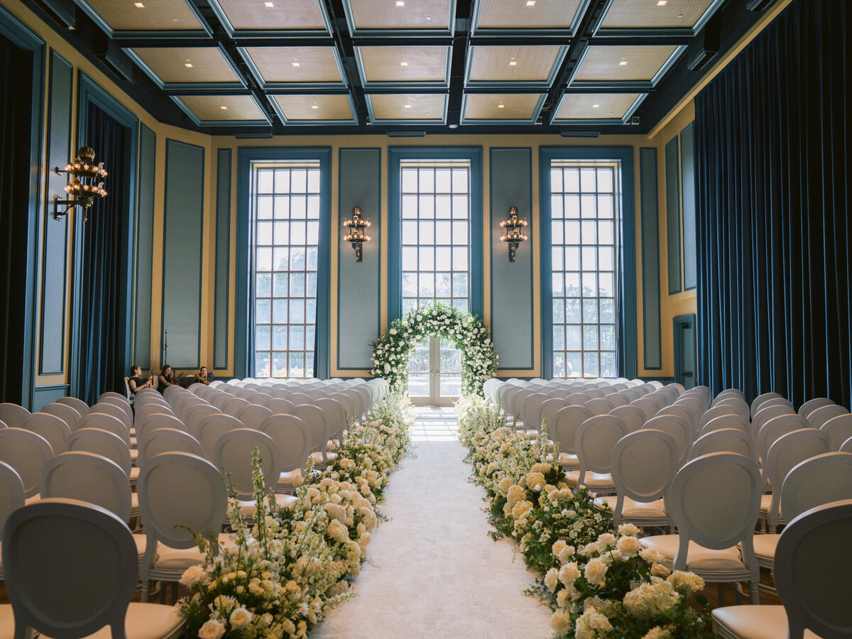 Wedding ceremony with white altar, white chairs, white flowers for black tie bespoke wedding