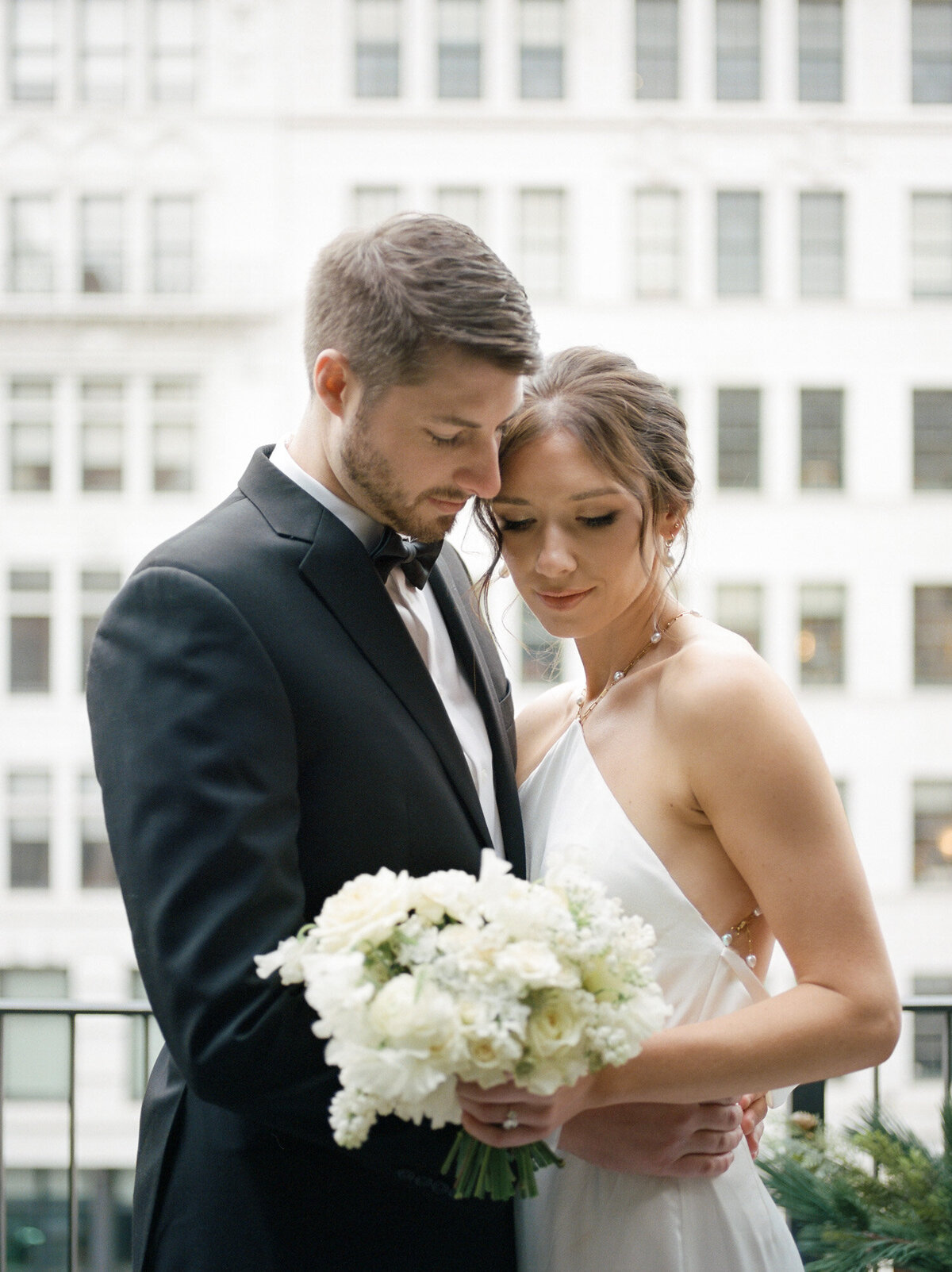 Michigan film wedding photographer captures couple embracing on Shinola Hotel balcony, white wedding bouquet