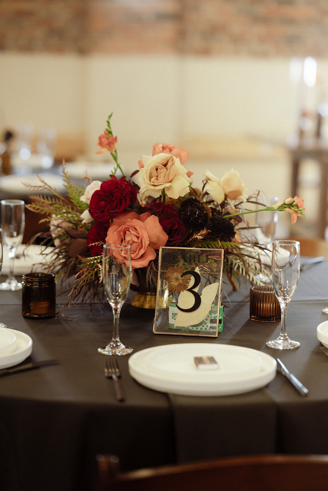 Burgundy, red, peach, and white floral centerpieces on a black tablecloth.