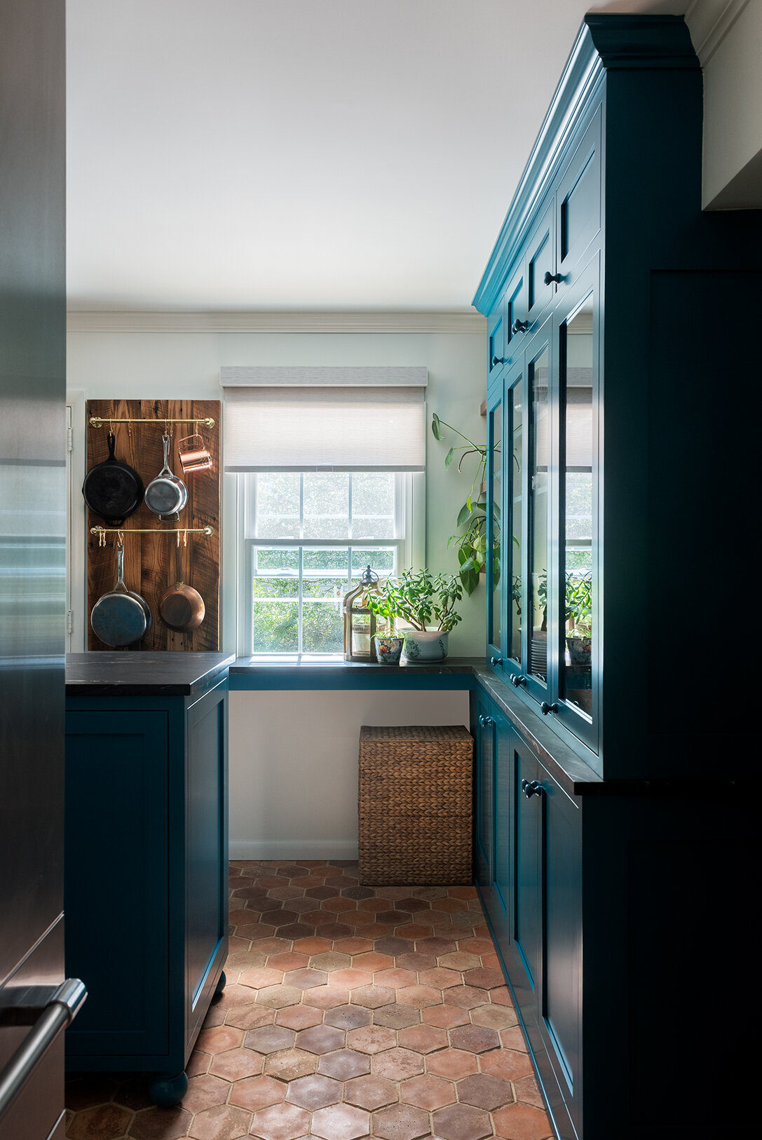 white kitchen with teal cabinets and window overlooking garden