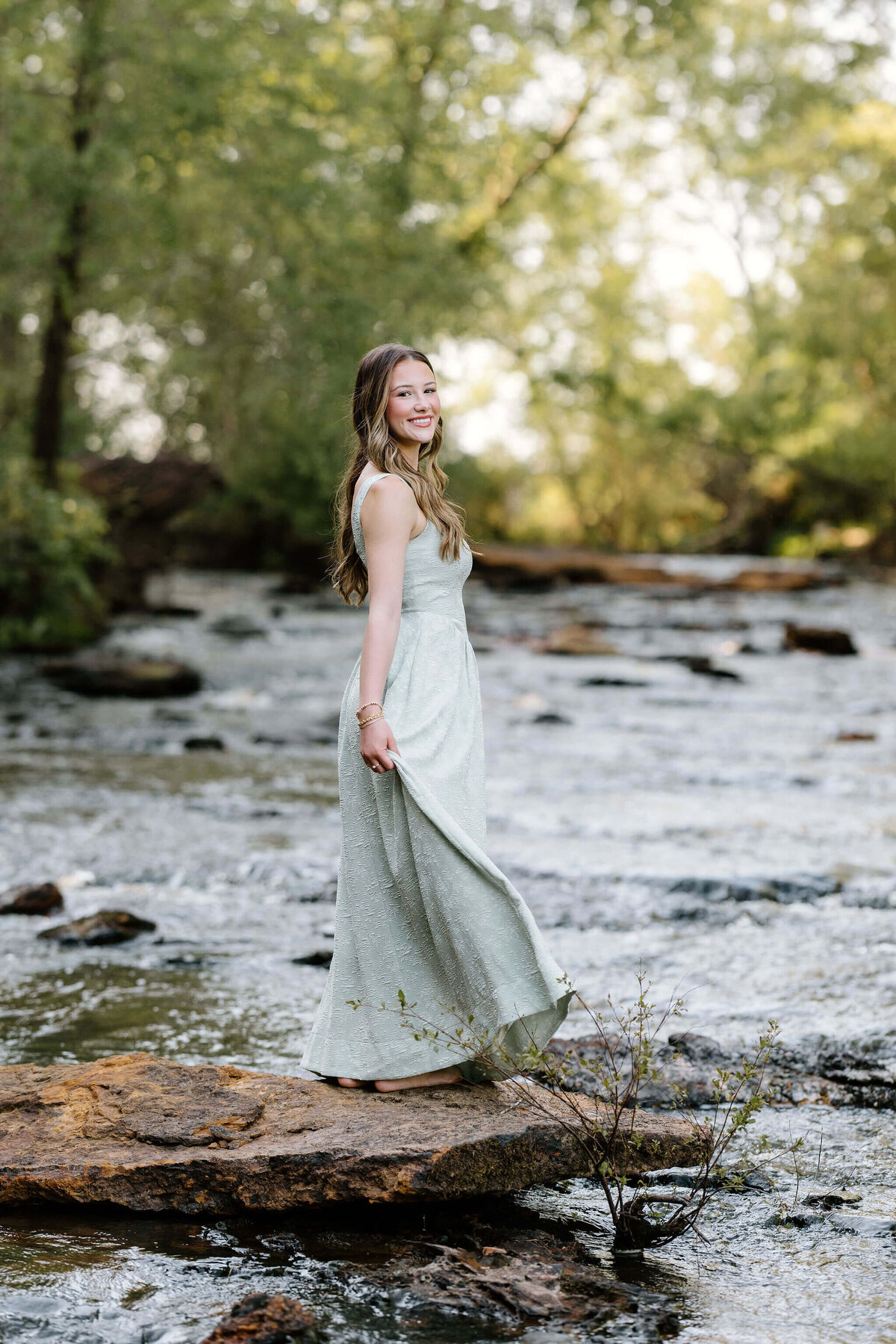 high school graduate wearing long light green dress standing in East Texas river