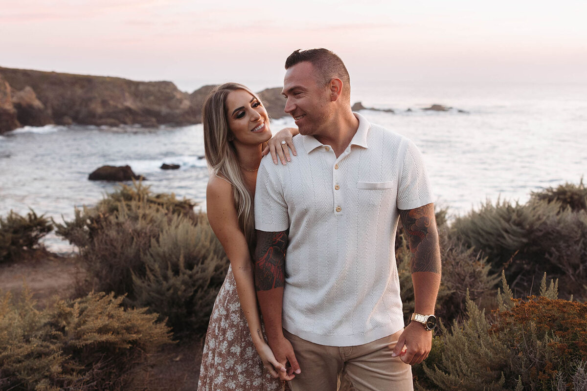 Couple laughing together on the coast at sunset