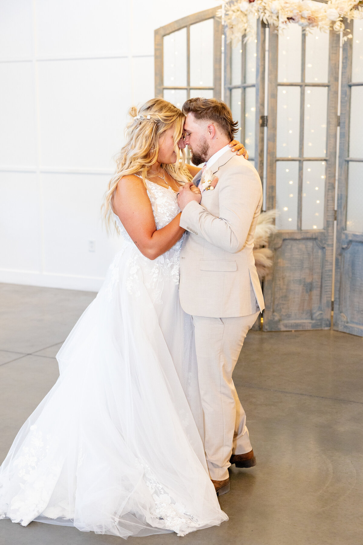 The bride and groom share an intimate first dance, holding each other close with their foreheads touching.