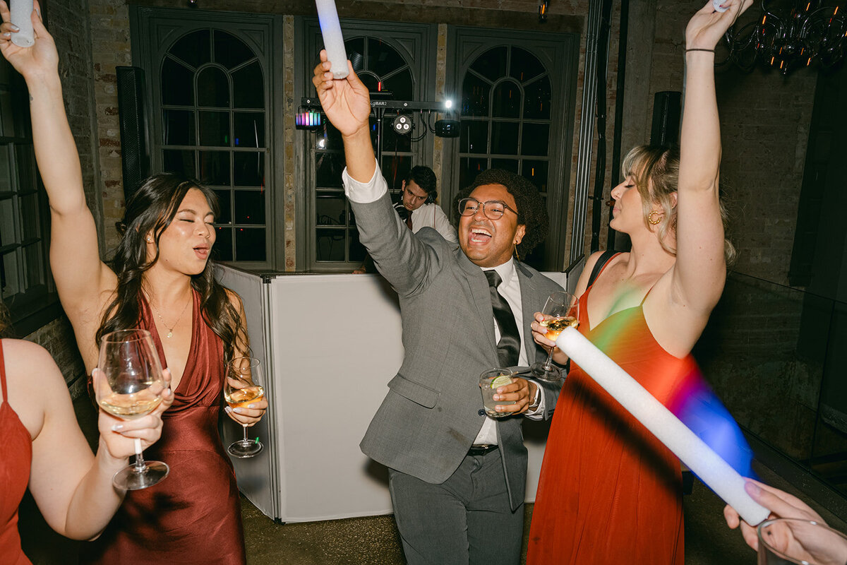 Wedding guests hyped on dance floor under colorful lights at San Antonio wedding after party