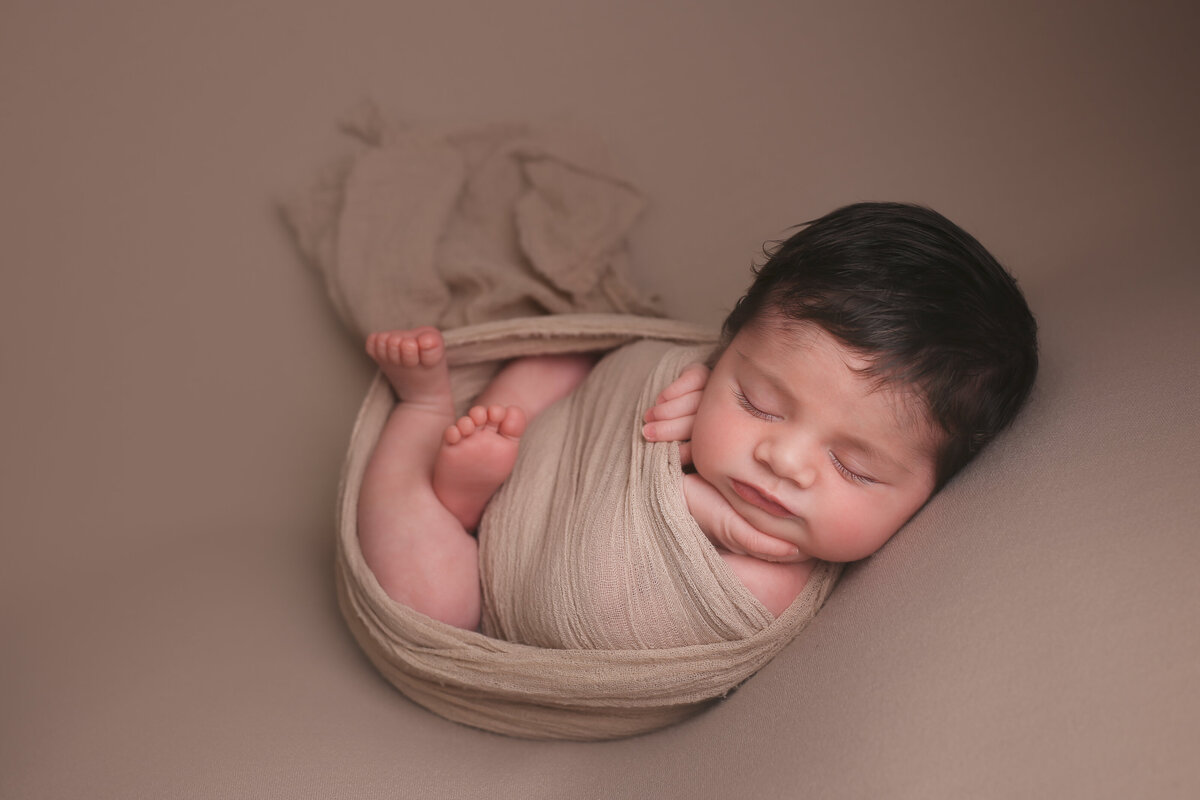 Newborn baby wrapped  and posed in brown wrap