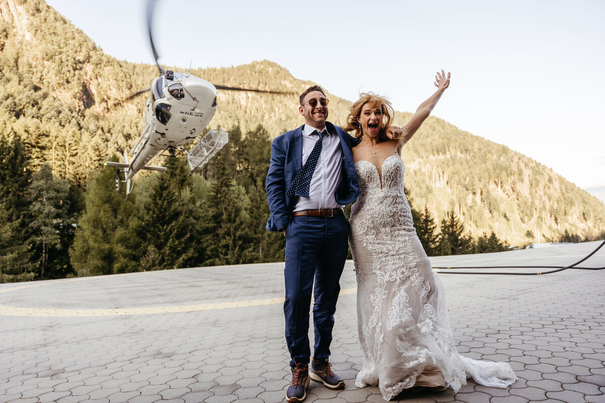 Bride and groom walking hand in hand toward helicopter on mountain plateau