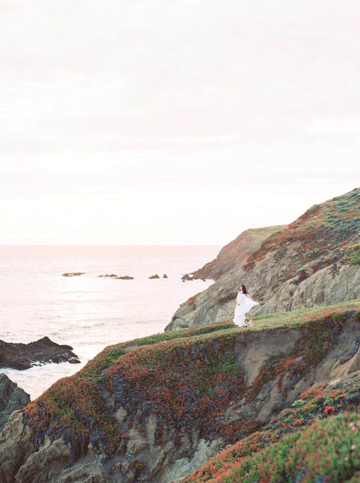 San Francisco maternity photography session on the coast with a woman wearing a white dress with a bouquet