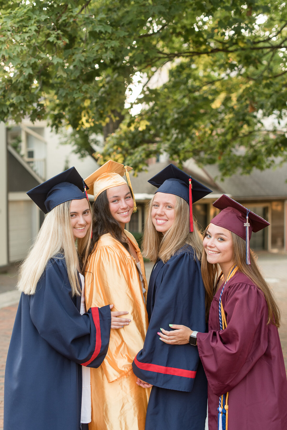 Four Senior girls each wearing their high school graduation cap and gown huddled together in Lancaster City.