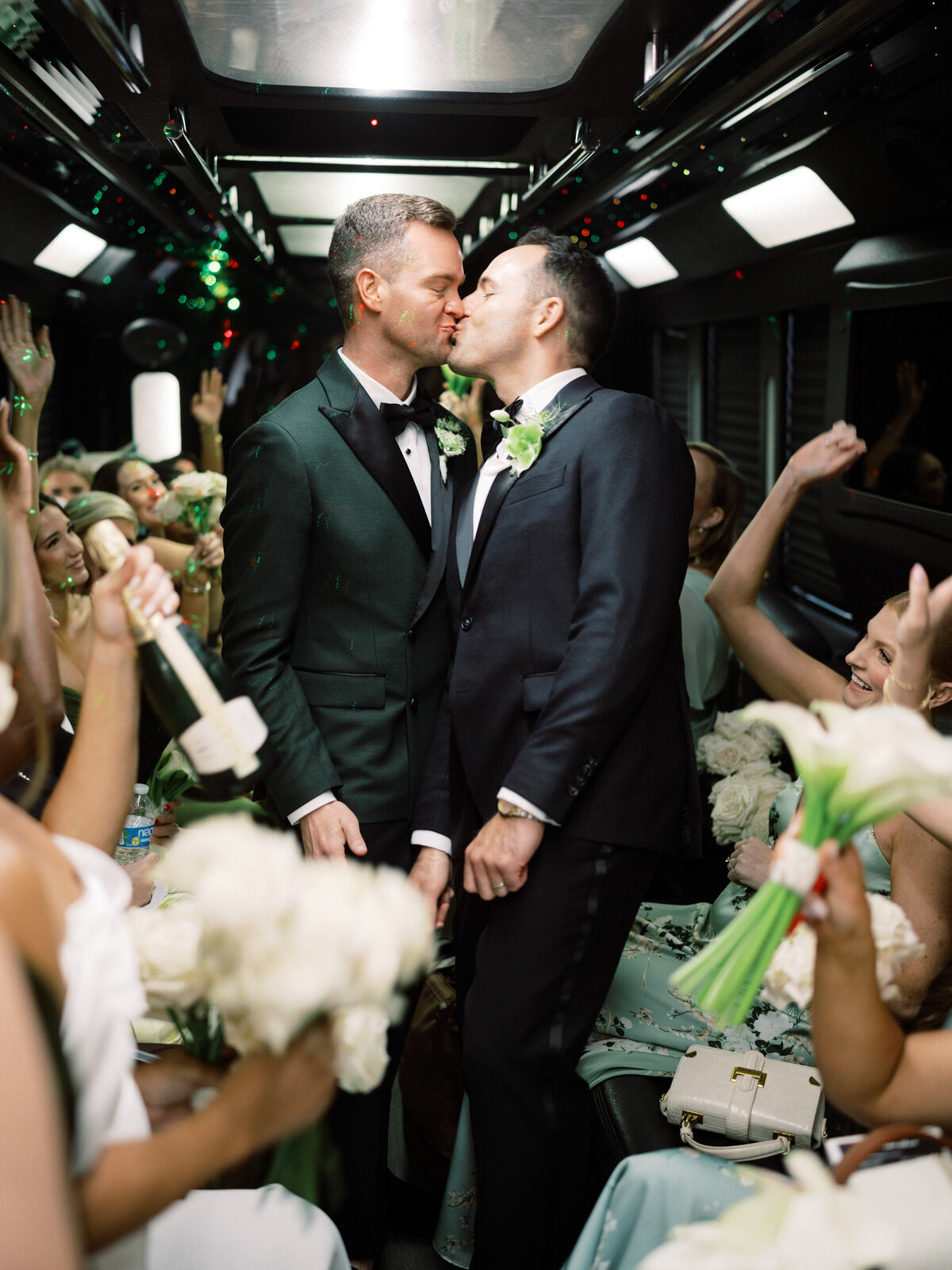 A joyful moment captured as a couple kisses on a party bus surrounded by energetic friends, celebrating love, unity, and excitement on their special day filled with fun.