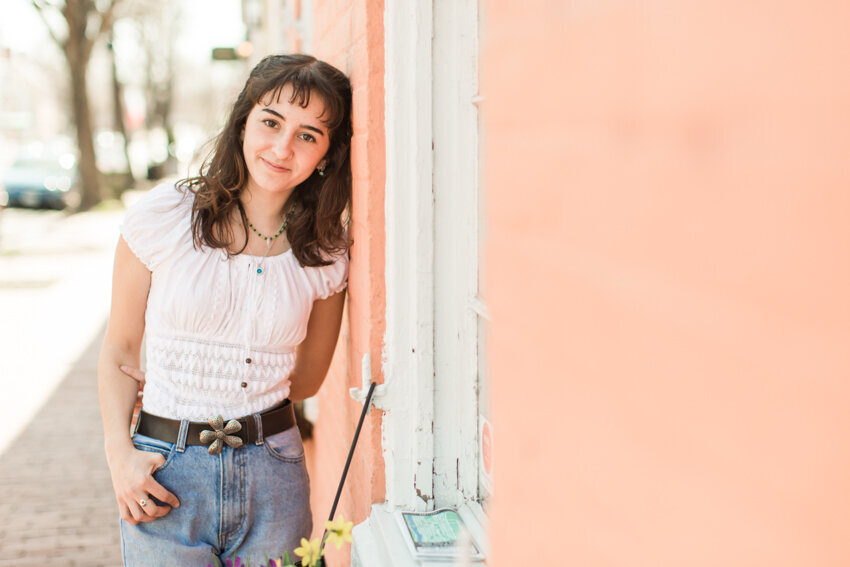 Senior girl leaning against pink wall