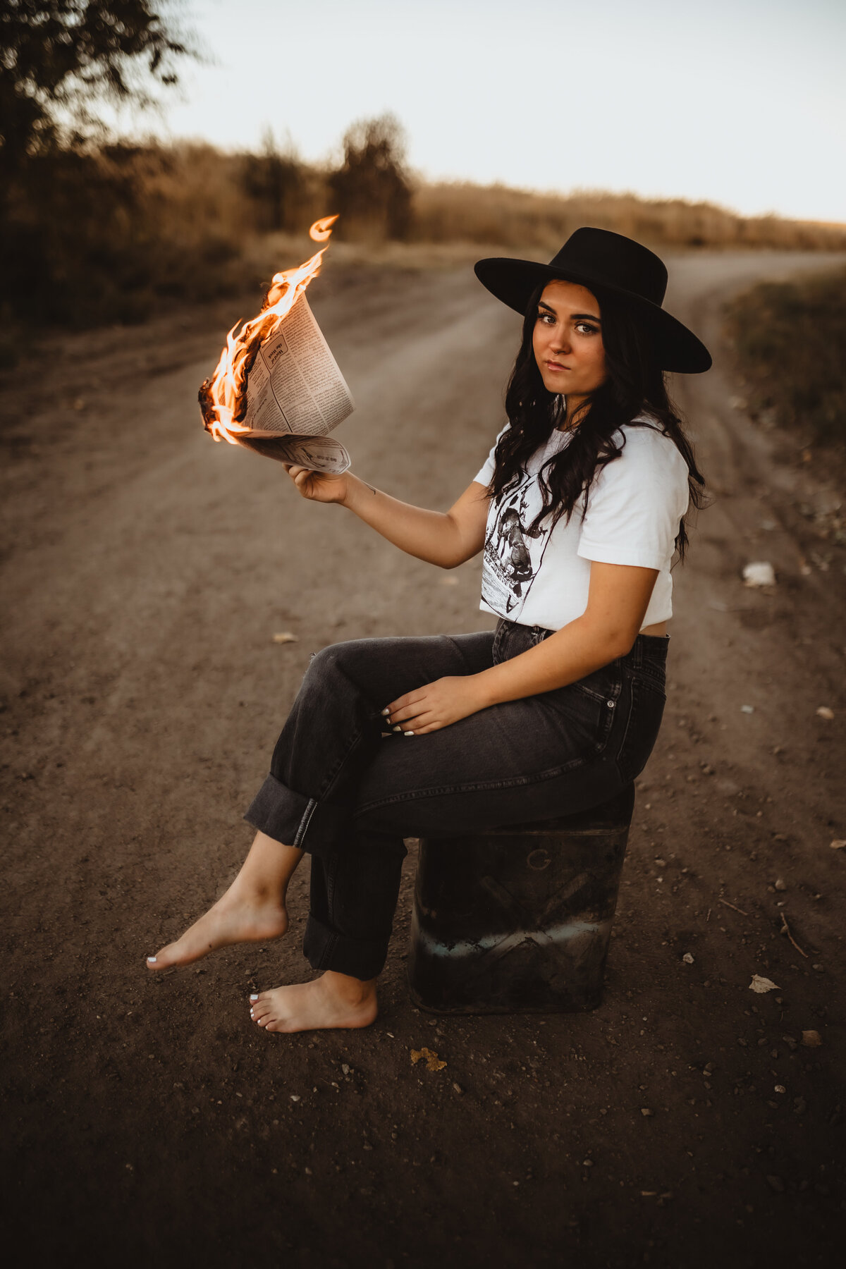 SENIOR SITTING ON GAS CAN HOLDING NEWSPAPER ON FIRE