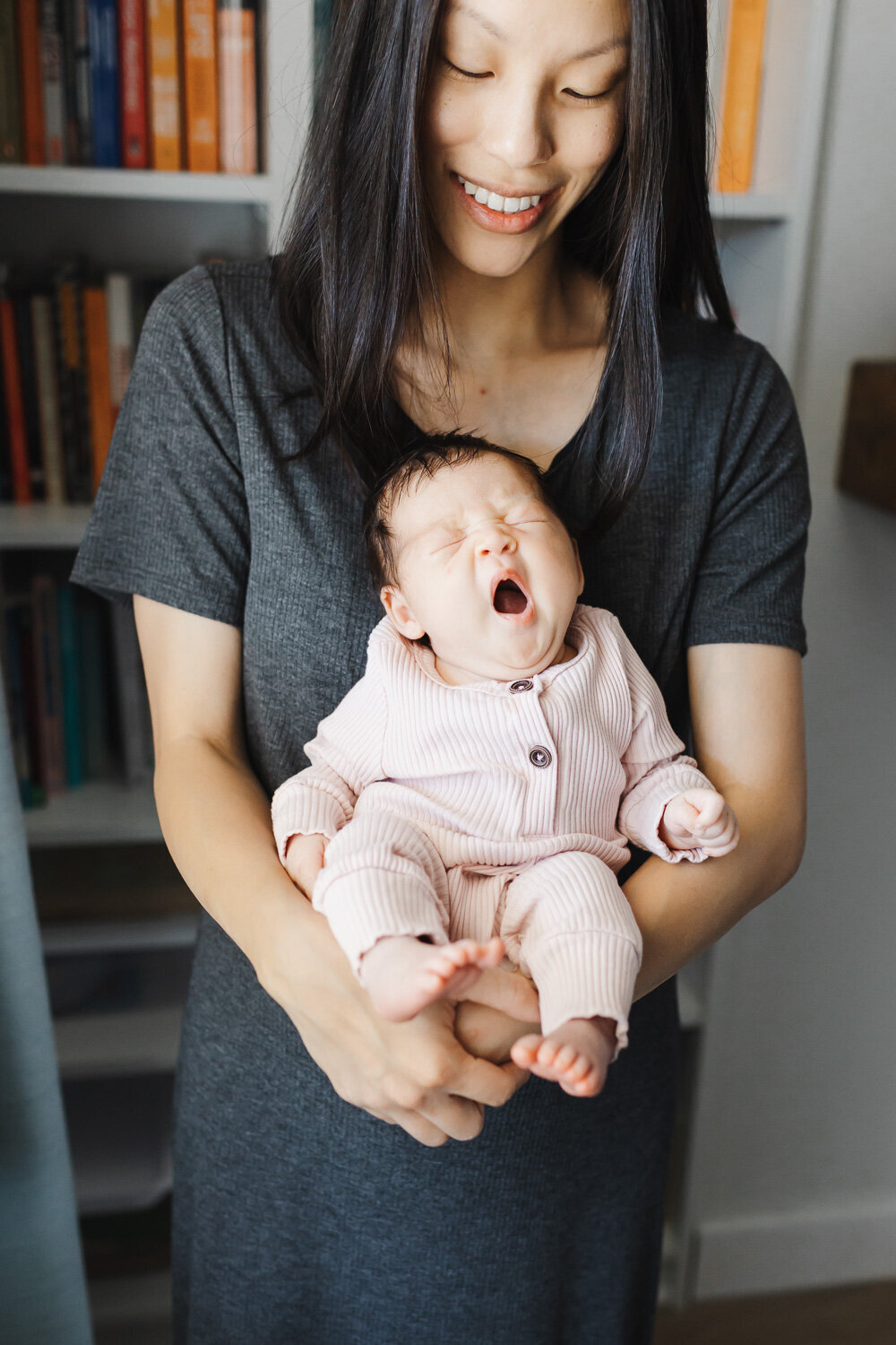 mom holding a yarning newborn baby girl