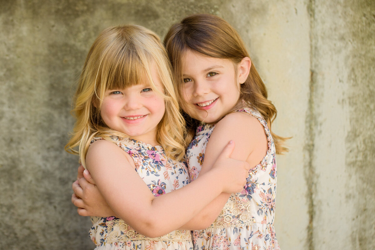 Two sisters hug eachother at their mini session photo shoot in Phoenixville