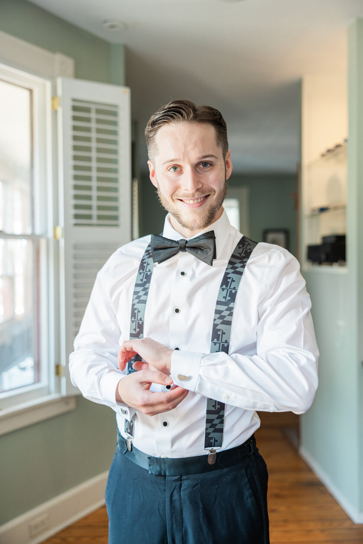 A groom adjusting the cufflinks on his shirt