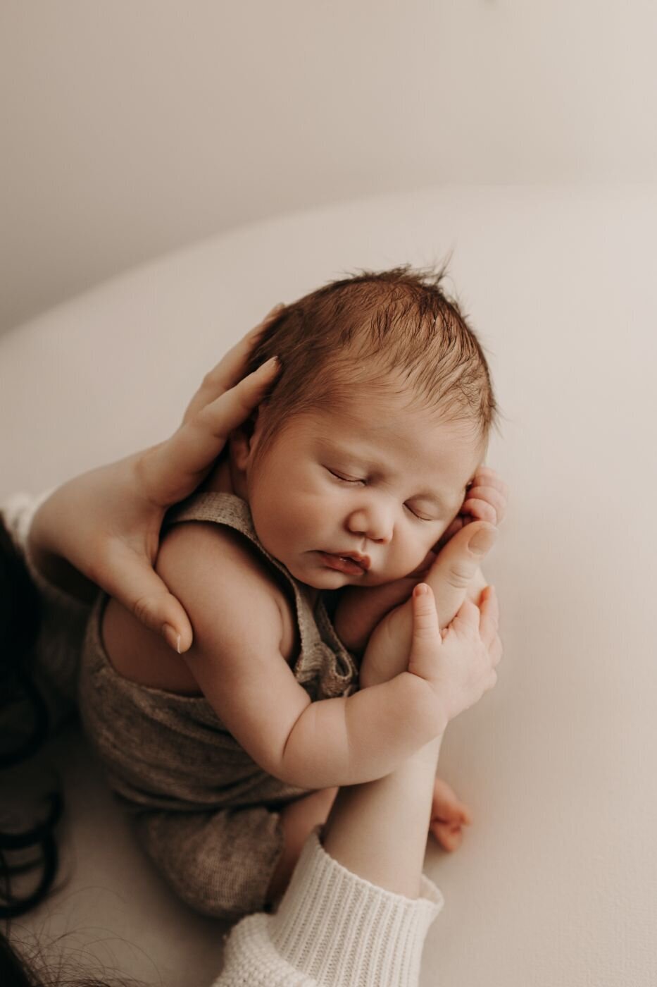 Serene newborn portrait of a baby being lovingly held on a soft surface in Mullingar, Ireland