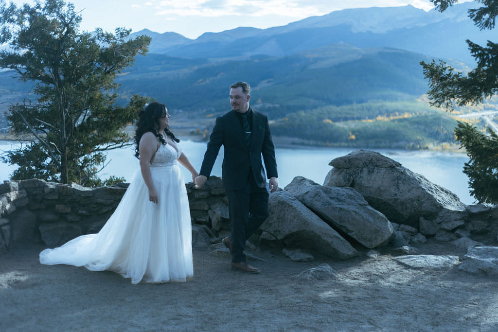 A couple holding hands and walking along a hiking trail.