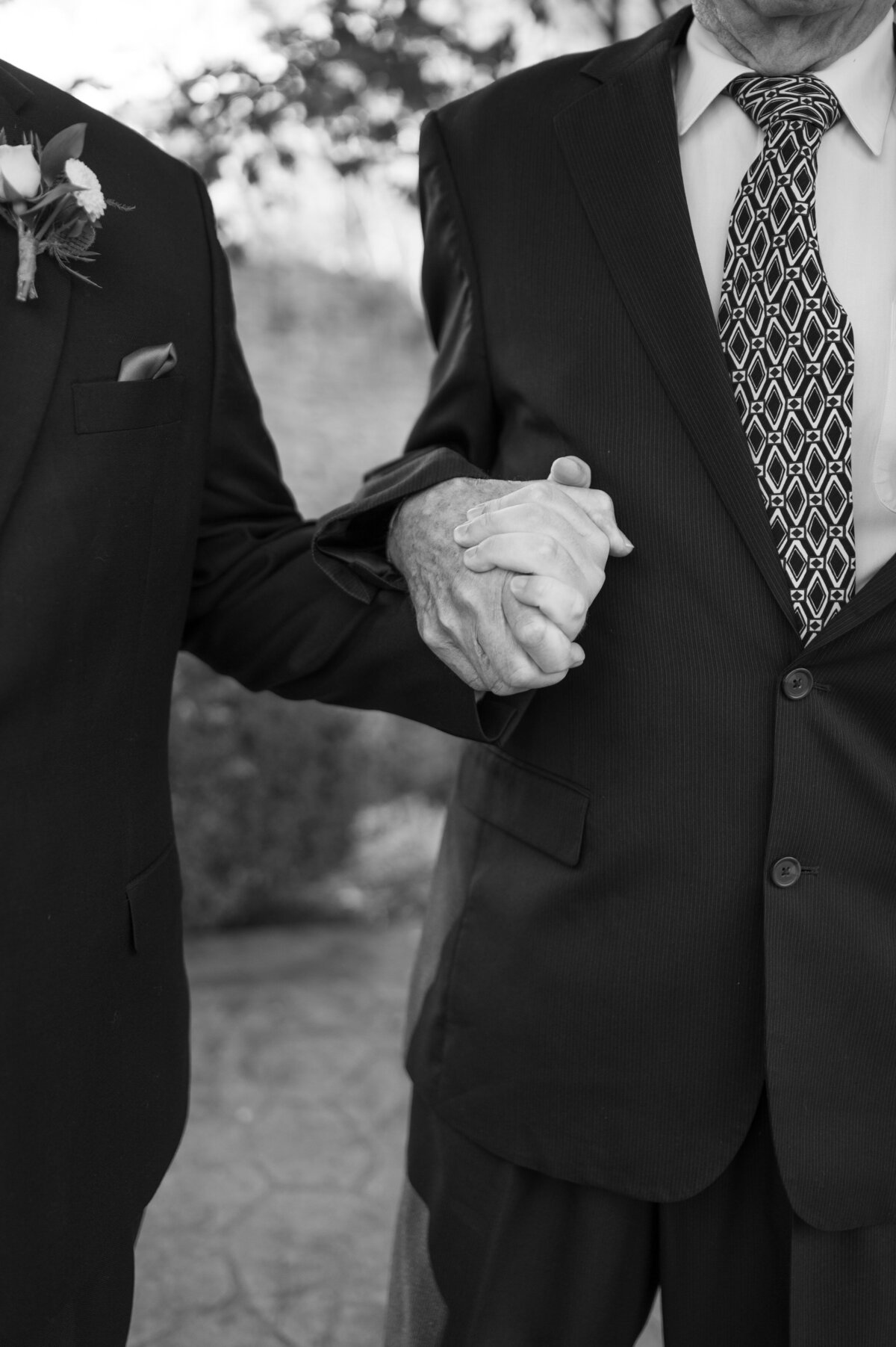 A close up of two people in suits holding hands