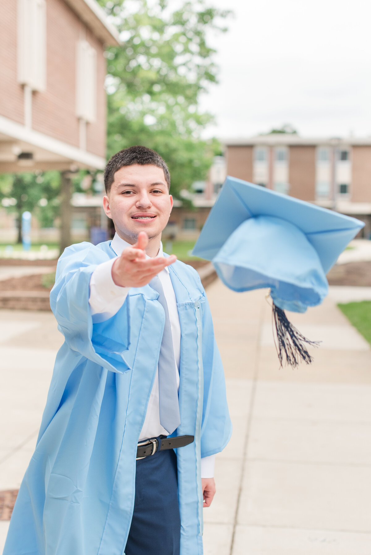 male grad throwing cap with blue gown