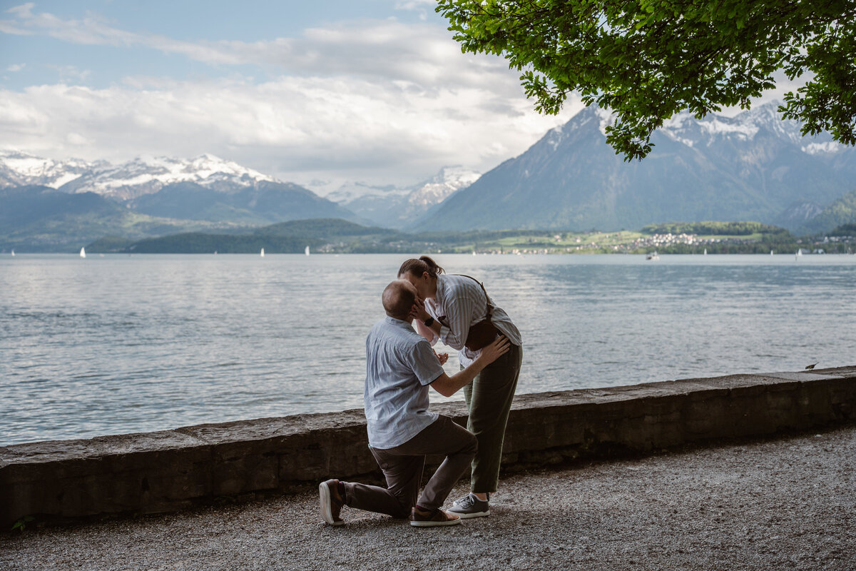 A person kneeling down next to a lake proposing
