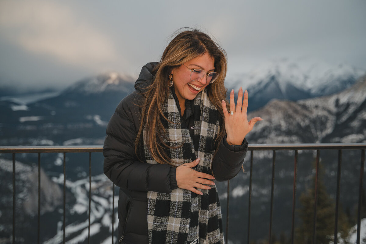 Newly engaged woman admiring her new engagement ring on top of Sulphur Mountain.