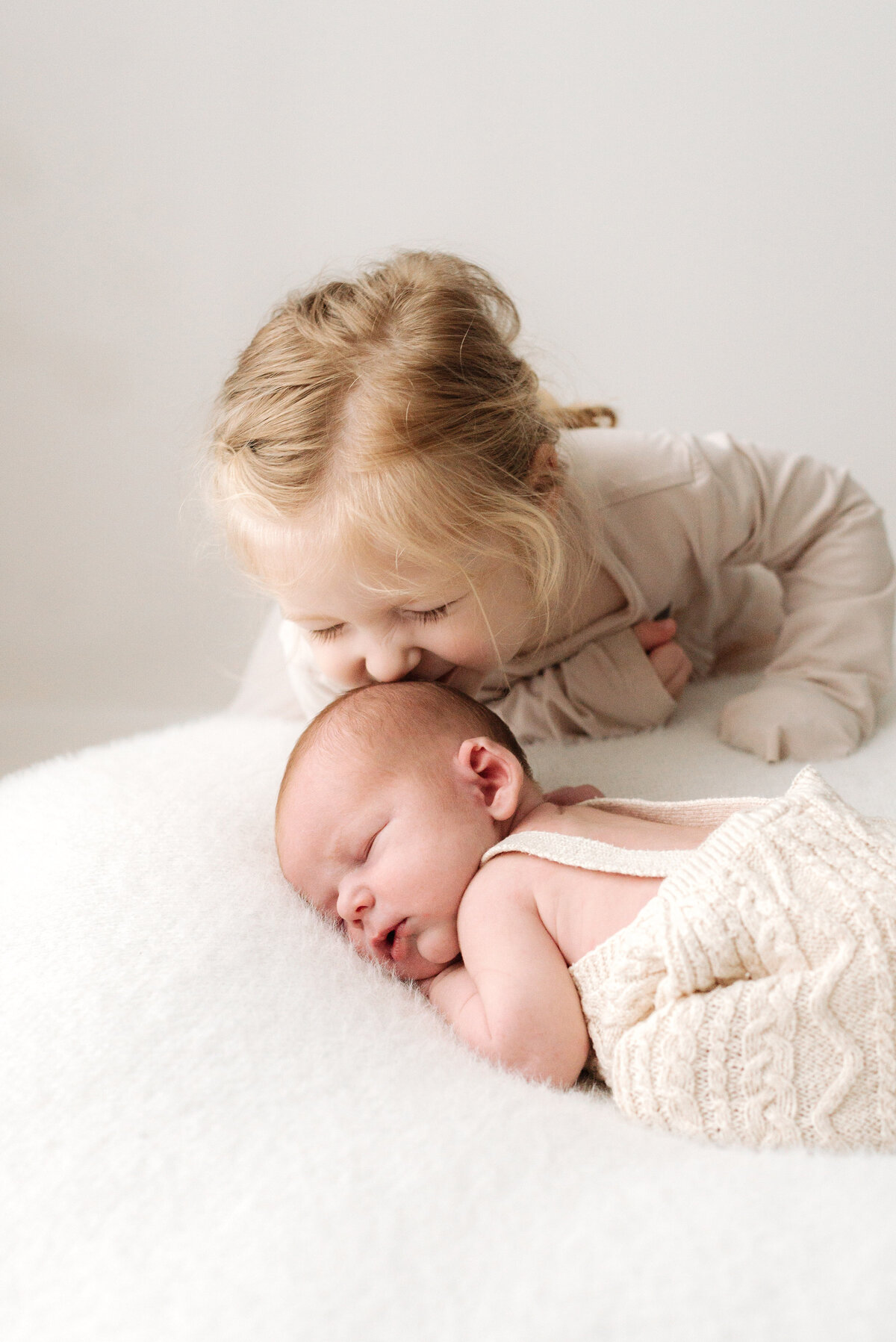 Little girl kissing her baby brothers head at west sussex newborn photoshoot