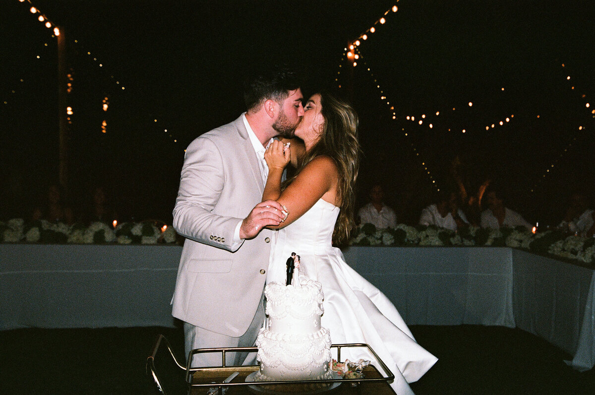 bride and groom kissing with cake shot on 35mmfilm