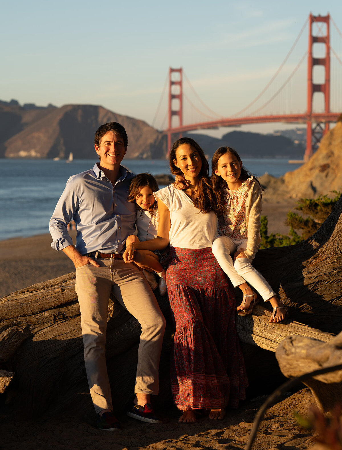 Family posing at the beach at sunset with the golden gate bridge in the background