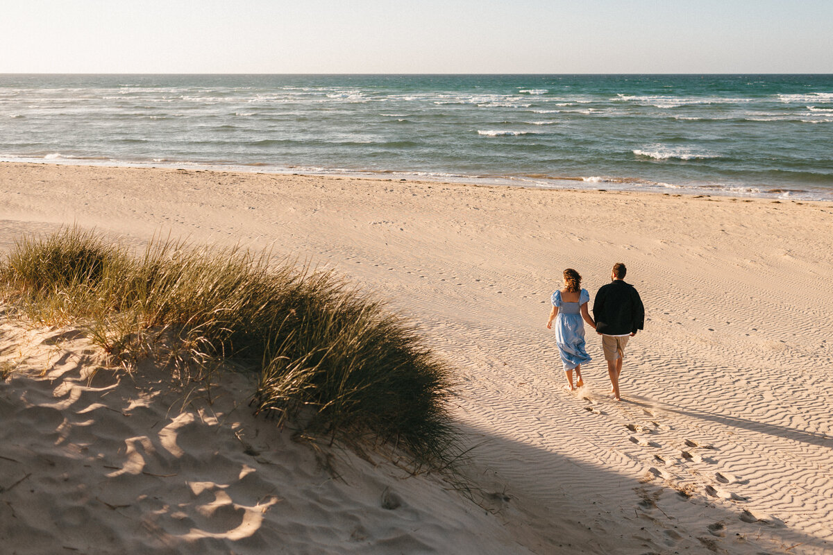 Couple walking towards the sea at a deserted west cornwall beach on a sunny evening in summer