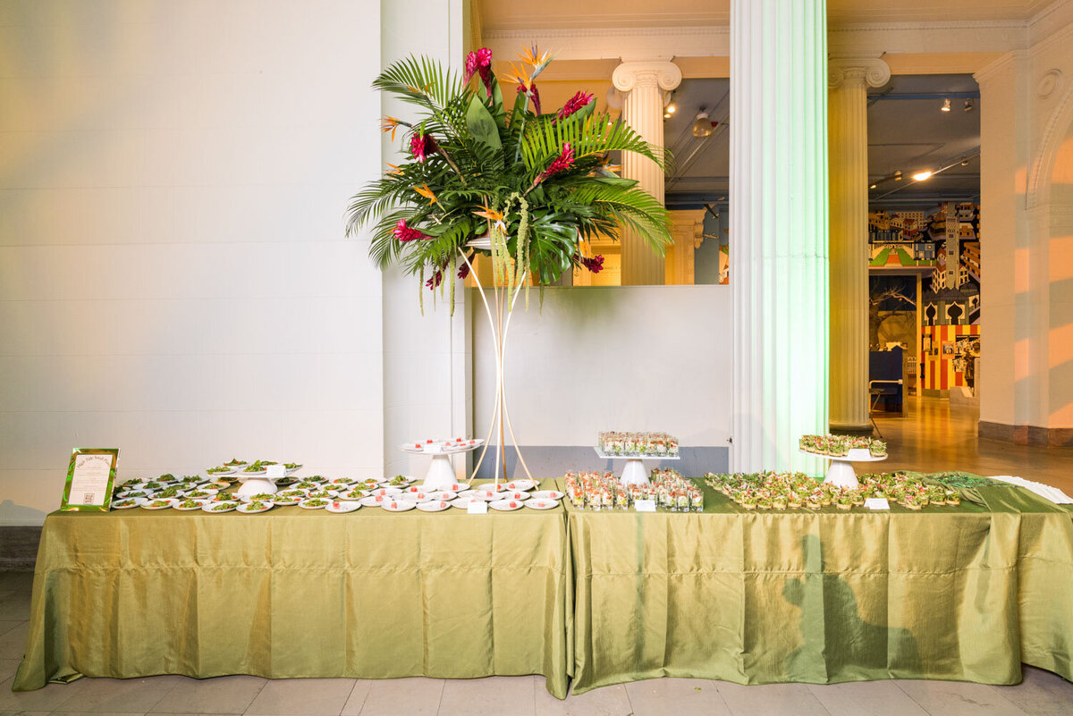 Buffet table with green cloth and tall tropical centerpiece