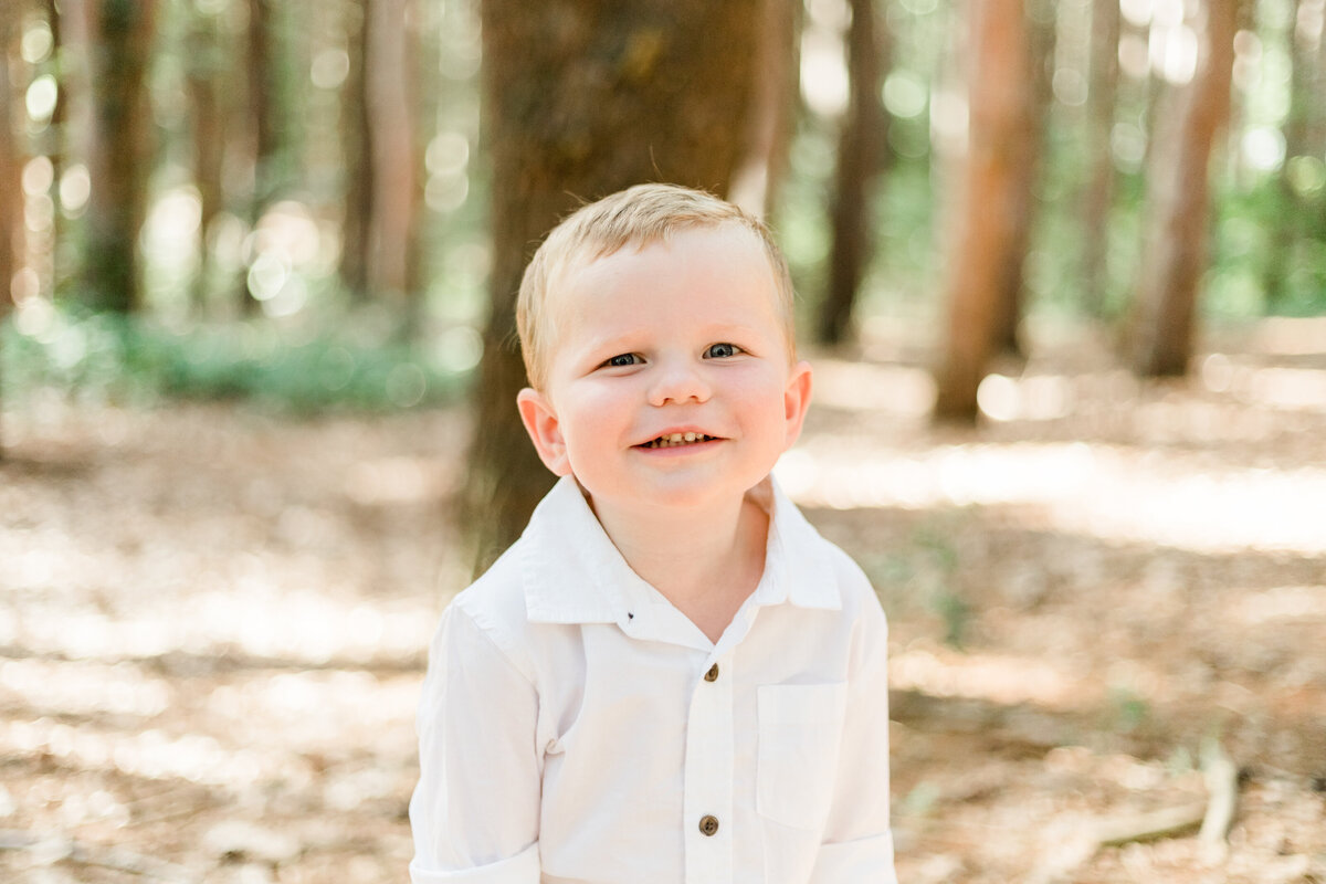 little boy smiling in the woods