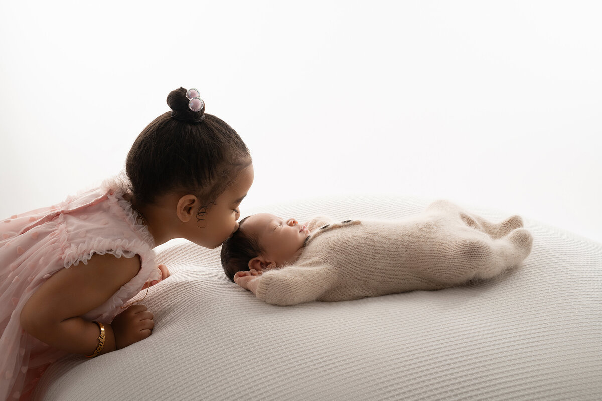 Syracuse photographer, newborn, baby, props, newborn photoshoot, photography, belly, backdrop, studio, white, backlit, sibling, kisses, onesie, pink dress, bean bag, black baby