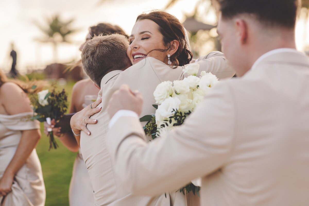 Groomsman hugging bride after wedding ceremony in Cancun