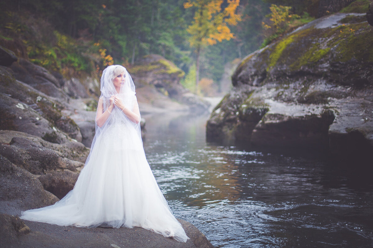 Misty and romantic wedding photo of a bride by a river.